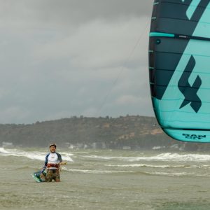 A kitesurfer enjoying a thrilling ride on the ocean waves under a cloudy sky.